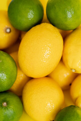 Top view of organic lemons and limes on yellow surface