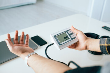 Close up of unrecognizable male patient using modern tonometer at home. Cropped of middle-eastern man measuring his blood pressure, making self checkup.