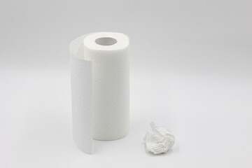 roll of white paper napkins for kitchen and cleaning and crumpled used white napkin on a white background