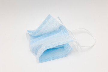 Fototapeta premium disposable blue used medical mask folded in half isolated on a white background