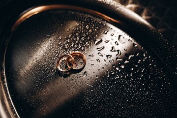 Macro photography wedding rings in water drops, engagement rings symbolizing love, with gold shades.