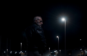Fototapeta na wymiar Adult man on street at night with lights of street lamps