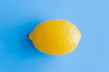 Top view of bright yellow lemon on blue background