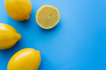 Top view of bright lemons on blue background with copy space