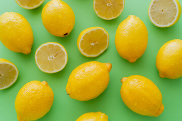 Top view of wet lemons on green background
