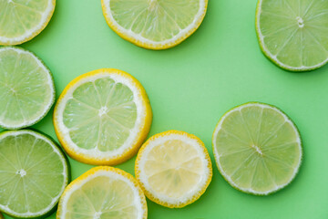 Fototapeta premium Top view of sliced lemons and limes on green background