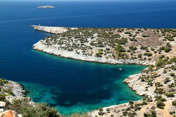 Obraz premium Mediterranean bay with azure water, boat, lighthouse on the edge of the earth and a small island in the background near the city of Alanya, Turkey