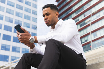 Serious black businessman talking on smartphone on street