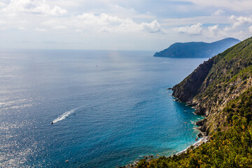 Fishing boats moored on water in harbor of Ligurian and Mediterranean Sea near coastline of Riviera di Levante of National park Cinque Terre Coast with blue sky, Riomaggiore village, Liguria, Italy.