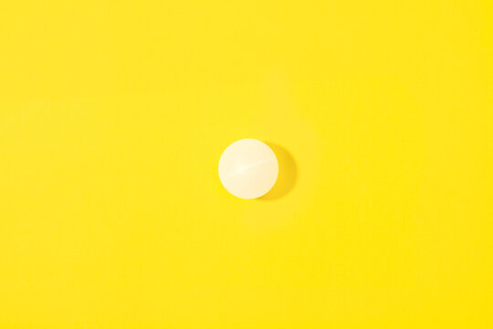 Pelota de ping-pong blanca proyectando sombra sobre un fondo amarillo brillante liso y aislado. Vista superior. Copy space