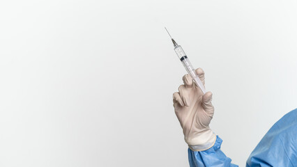 Doctor or nurse wearing protective suit and mask is holding a disposable injector 