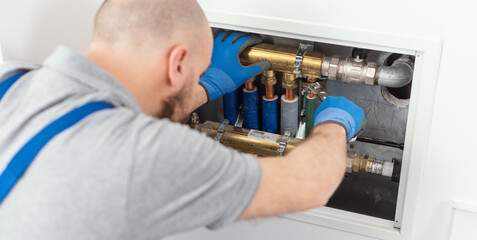 Naklejka na ściany i meble Professional plumber installing plumbing manifolds