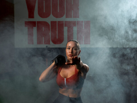 Determined young sportswoman doing lunges with dumbbell in gym - Powered by Adobe