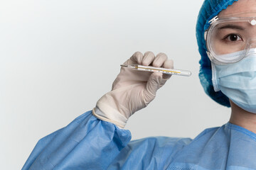 Female doctor or nurse wearing protective suit is holding a thermometer