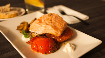simmered slice of salmon with tomato spinon and coconut sauce on a white plate