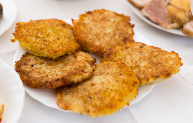 Fried grated potato pancakes with sour cream on white plate