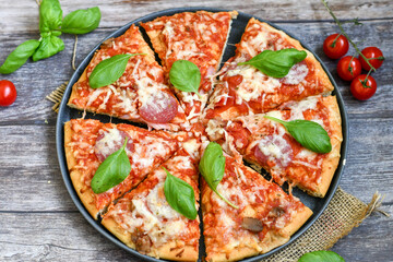  Close up of   classic  Italian Pizza   with Ham and salami . Fresh basil,tomato sauce ,mozzarella cheese , mushrooms and  green peppers