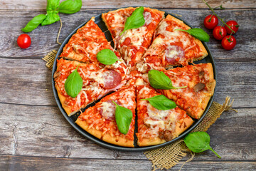  Close up of   classic  Italian Pizza   with Ham and salami . Fresh basil,tomato sauce ,mozzarella cheese , mushrooms and  green peppers