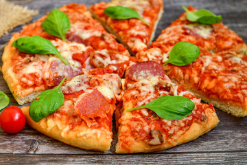  Close up of   classic  Italian Pizza   with Ham and salami . Fresh basil,tomato sauce ,mozzarella cheese , mushrooms and  green peppers