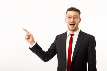 A young businessman in a business suit points to copyspace.