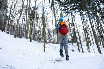 Hiker in uphill icy mountain trail wearing crampons on hiking boots.
