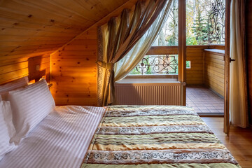 Obraz premium Cozy mansard bedroom with natural wood trim with double bed and balcony