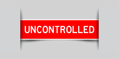 Inserted red label sticker with word uncontrolled on gray background