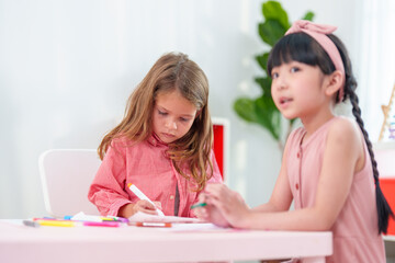 Adorable girls being creative with colourful pencils at kindergarten. Kindergarten playtime activities.