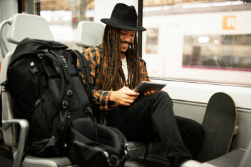 Young man using digital tablet while traveling by a train. Handsome young man traveling by a train.