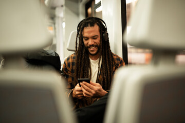 Young man listening the music while traveling by a train. Handsome young man traveling by a train..