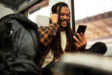 Fototapeta premium Young man listening the music while traveling by a train. Handsome young man traveling by a train..