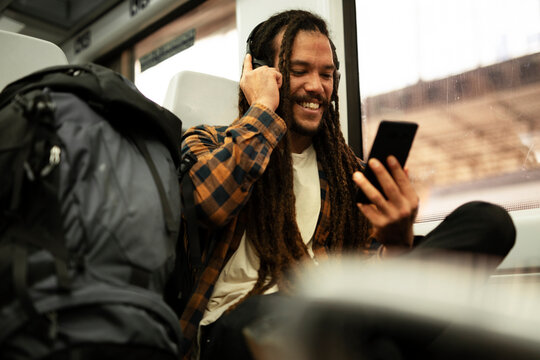 Young man listening the music while traveling by a train. Handsome young man traveling by a train..