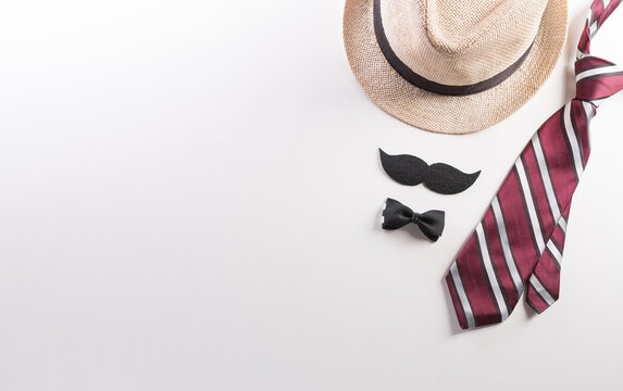 Happy Fathers Day background concept with hat, gift box, necktie and mustache on white background.