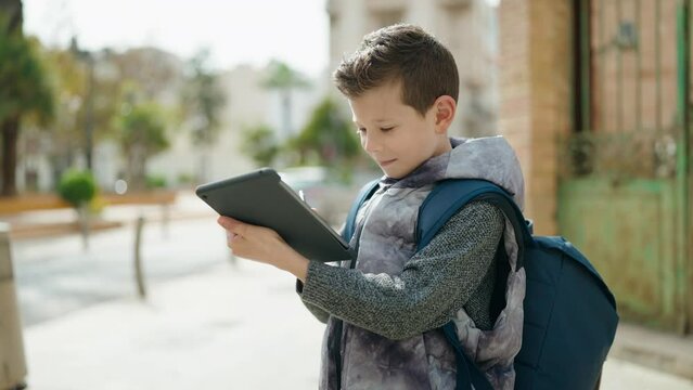 Blond child student using touchpad standing at street