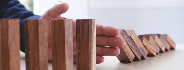 Protection finance from domino effect concept. Hands stop domino effect before destroy stack of...