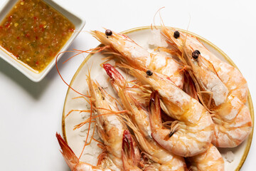 Baked salted banana shrimp (Penaeus merguiensis) usually serve with spicy sauce. Top view isolated on white background.
