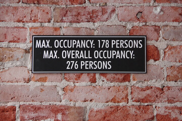 MAX. OCCUPANCY sign on an old building inside brick wall