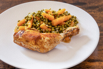 top view of a chicken leg with peas carrots