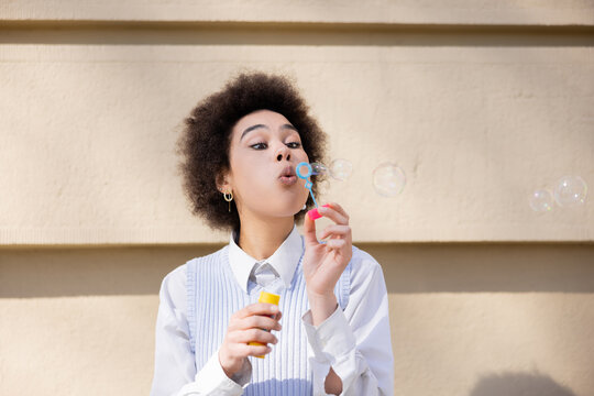 Curly African American Woman Blowing Soap Bubbles