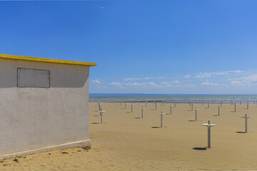 Obraz premium Panoramic view to Grado Adriatic sea beach with tiny white building under blue sky on sunny spring day