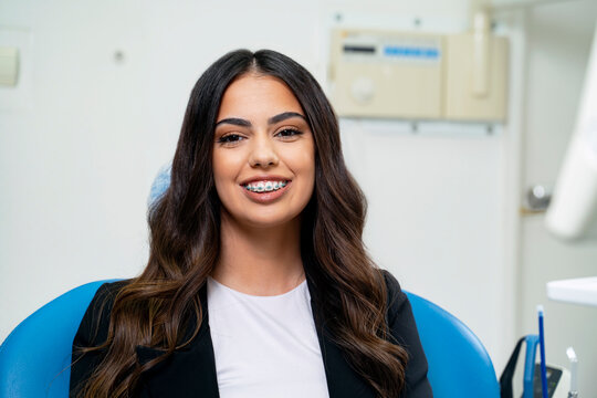 Elegant young adult woman sitting in dental chair, dental braces concept 