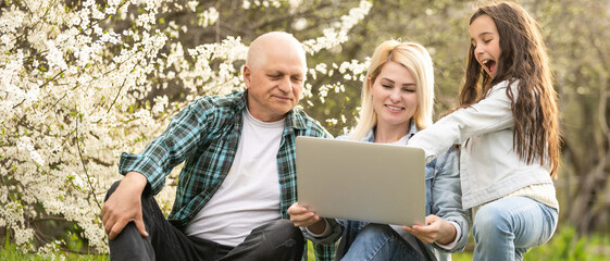Elderly man explains how to use a laptop to his granddaughter.
