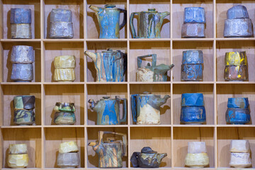 There are handmade ceramic pots on the shelf. Pottery.