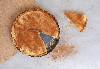 Traditional South African milk tart freshly baked and in tin with one slice cut out on  Mottled...