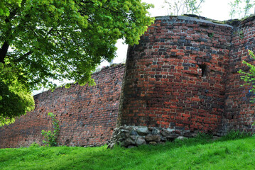 Zdjęcie architektury przedstawiające fragment murów obronnych z basztą