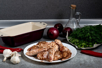 Raw chicken wings with spices on a white plate on the kitchen table. Preparing for barbecuing.