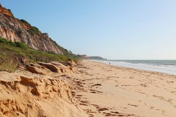 Orange cliff with land falling over the beach. Lots of orange sand and calm sea. Taipe Beach, Trancoso, Bahia, Brazil