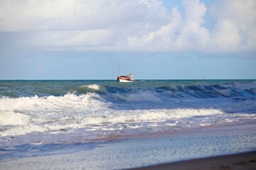 Small colorful boat floating over blue ocean water. Clear sky in the horizon, waves on the sea.,