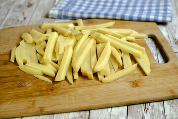 sliced potatoes ready to be fried on a wooden board