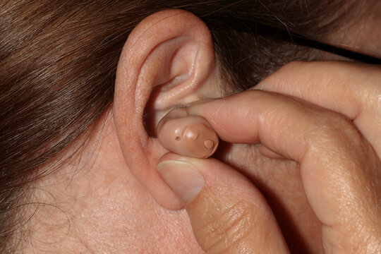 Close-up of a woman's finger inserting a hearing aid in her ear